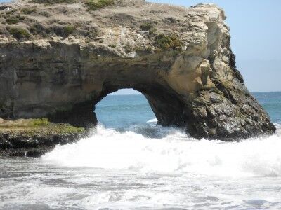 Waves crashing through Natural Bridge at Natural Bridges State Beach in California